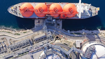 Photo shows an aerial view of a LNG barge in water at the port of a gas facility